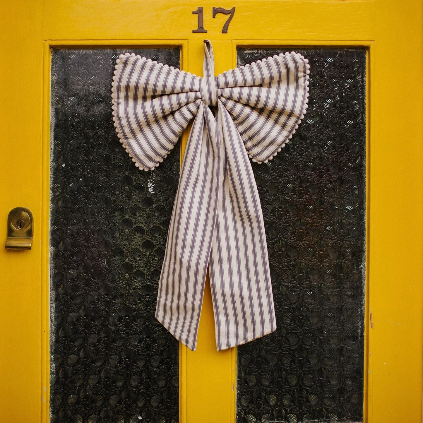 A large decorative grey stripe bow with mini pom pom trim and a ribbon hang tie