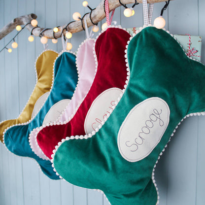 Velvet dog bone shaped personalised stocking. Lined in cotton with a pom pom trim. Embroidered personalised tag.