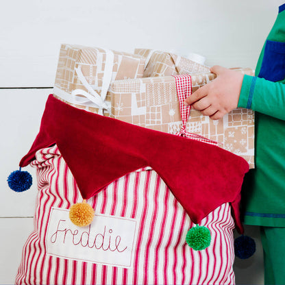 Personalised Christmas sack with pom pom details and embroidered personalised tag.