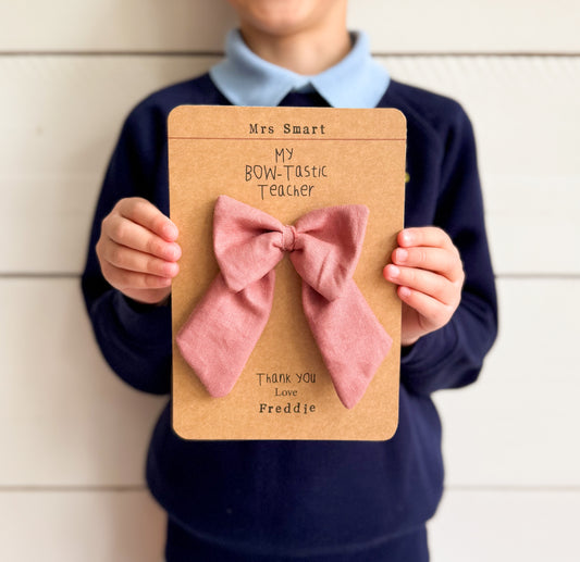 A handcrafted dusky pink linen bow attached to card and finished with handstamped personalised teacher and student names.
